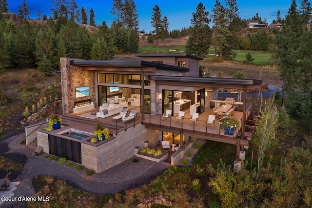 back of property featuring stone siding, an outdoor hangout area, and a garden