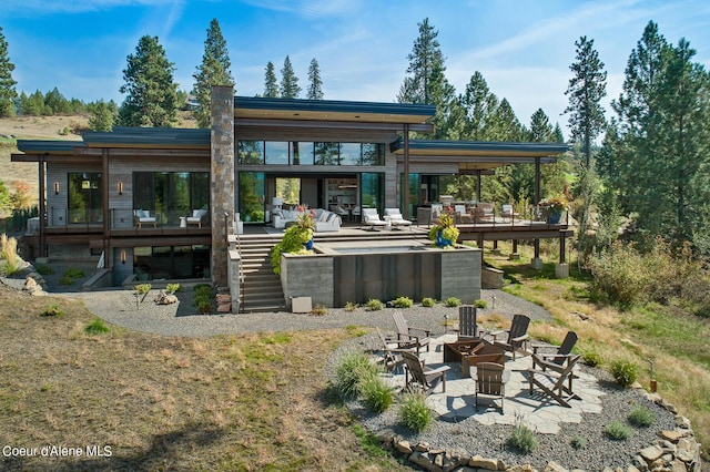 rear view of property with a deck, stairway, a fire pit, and a patio