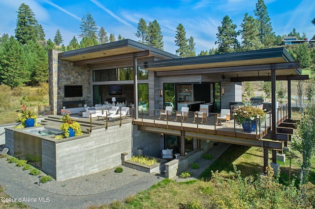 back of property with stone siding, an outdoor hangout area, and a patio area