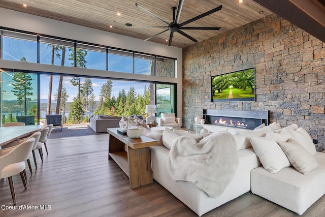 living room featuring hardwood / wood-style floors, recessed lighting, wooden ceiling, a fireplace, and a high ceiling