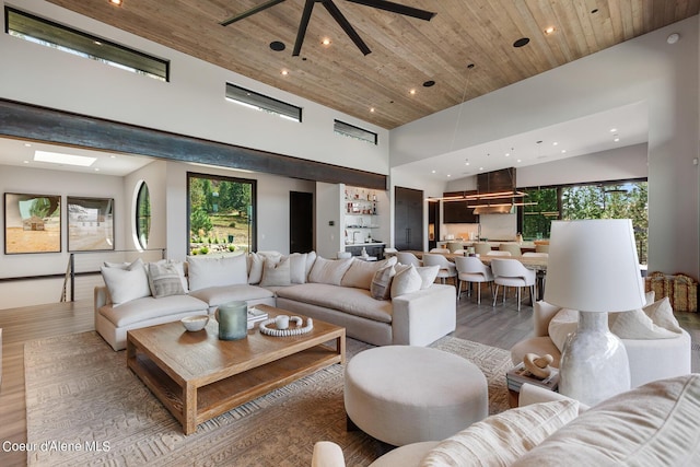 living area with recessed lighting, light wood-style flooring, wood ceiling, and a high ceiling