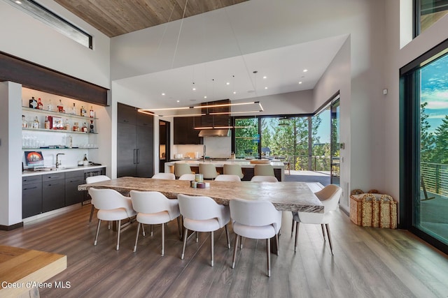 dining room with wet bar, wood finished floors, and a towering ceiling