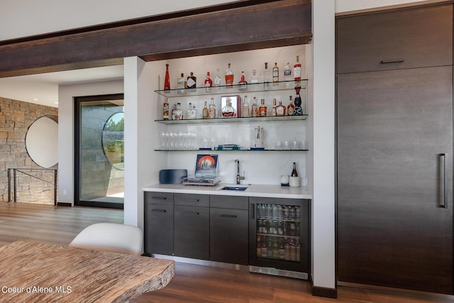 bar featuring wine cooler, paneled built in refrigerator, dark wood finished floors, and indoor bar