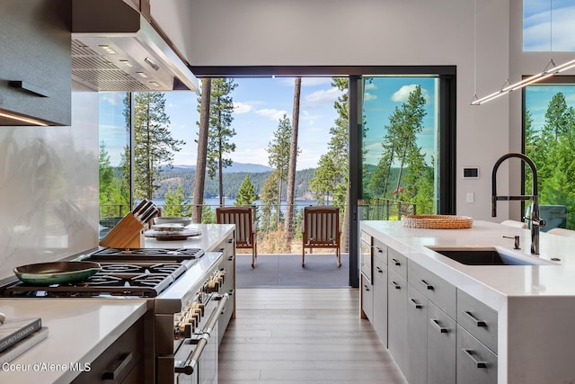 kitchen with range with two ovens, a sink, light countertops, under cabinet range hood, and a mountain view