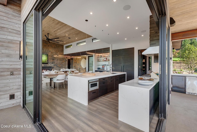 kitchen with a spacious island, oven, a sink, light countertops, and modern cabinets