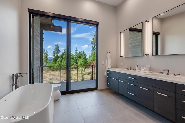 full bath featuring a sink, a freestanding tub, double vanity, and tile patterned floors