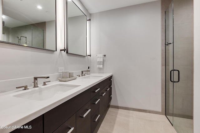 bathroom with double vanity, a stall shower, baseboards, and a sink