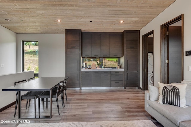 dining area featuring light wood-style flooring, recessed lighting, wooden ceiling, stacked washer / dryer, and baseboards