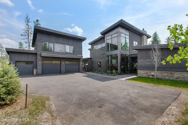 contemporary house with an attached garage, a chimney, and driveway