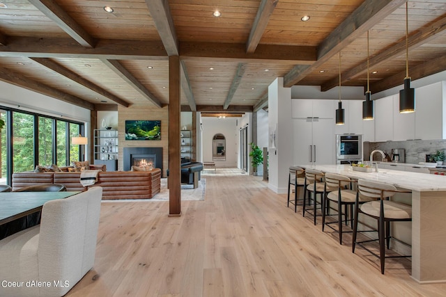 kitchen with light wood-type flooring, modern cabinets, tasteful backsplash, a breakfast bar area, and wooden ceiling