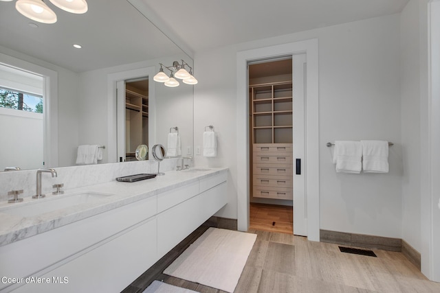 full bathroom with visible vents, wood finished floors, a walk in closet, and a sink