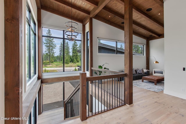 corridor featuring beam ceiling, wooden ceiling, a wealth of natural light, and hardwood / wood-style floors