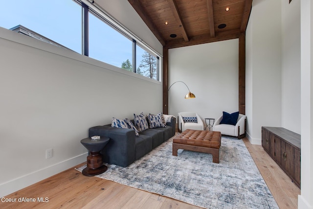 living area with baseboards, beam ceiling, wood ceiling, and light wood-style flooring