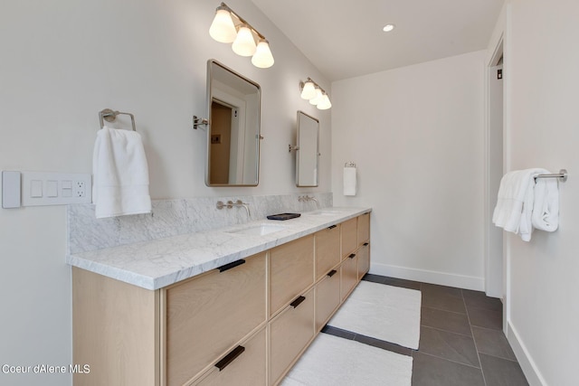 full bath featuring tile patterned flooring, double vanity, baseboards, and a sink