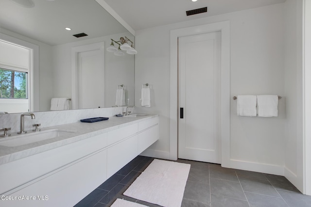 bathroom featuring a sink, visible vents, double vanity, and tile patterned floors