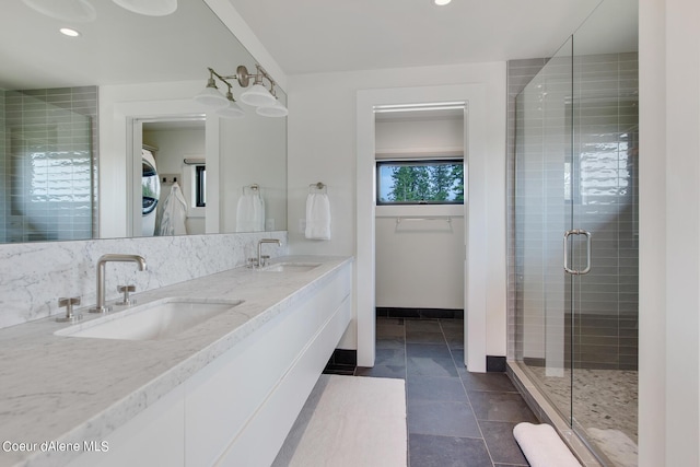 bathroom with a sink, baseboards, a spacious closet, and a shower stall