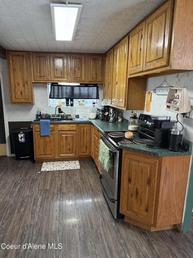 kitchen with stainless steel electric range oven, dark countertops, brown cabinets, and dark wood-style flooring