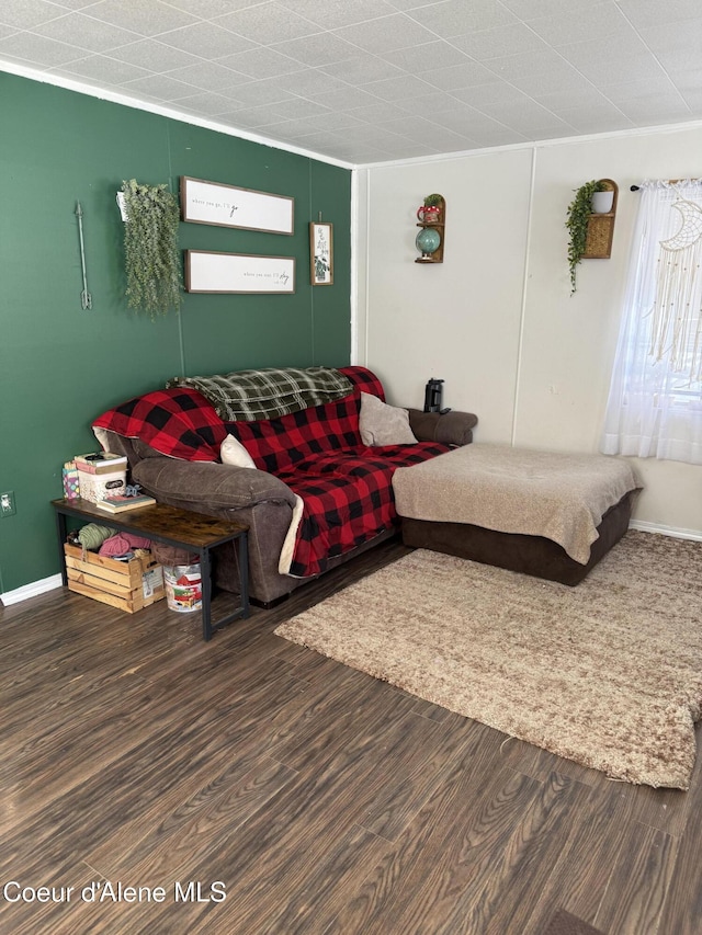 living area with baseboards, wood finished floors, and crown molding