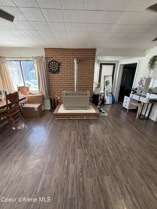 unfurnished living room featuring brick wall, a wood stove, and wood finished floors