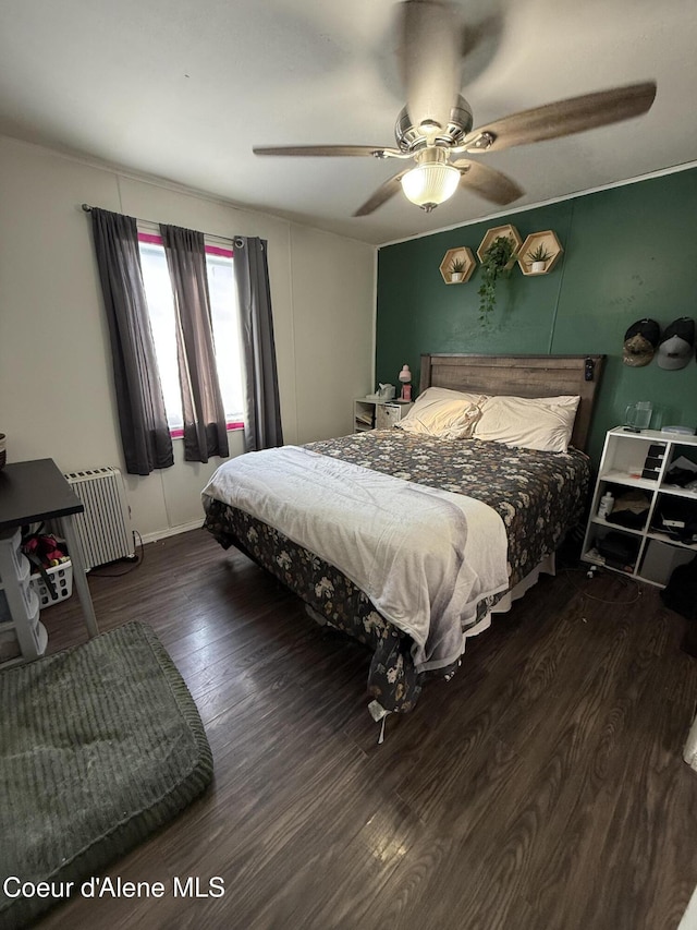 bedroom featuring a ceiling fan, radiator, and wood finished floors