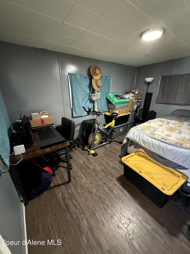 bedroom with a paneled ceiling and wood finished floors