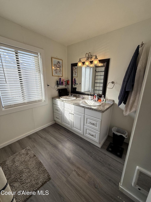 full bath with double vanity, visible vents, wood finished floors, and a sink