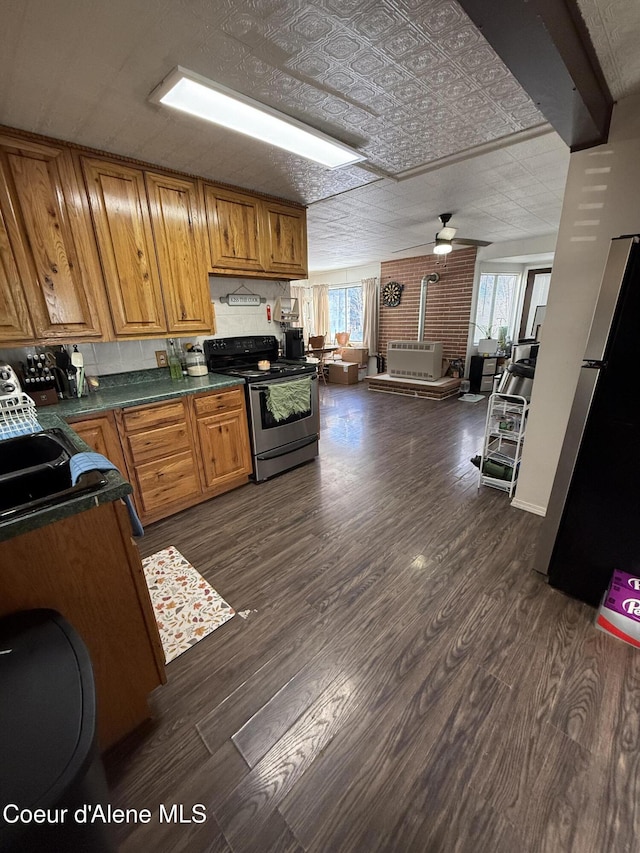 kitchen with an ornate ceiling, stainless steel electric stove, dark countertops, dark wood-style floors, and freestanding refrigerator