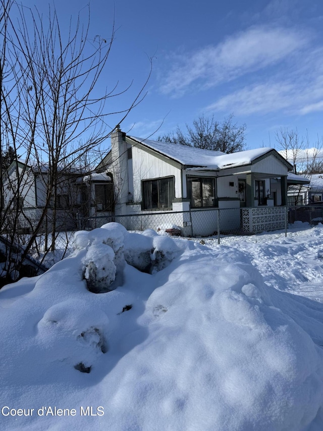 snow covered property featuring covered porch and fence