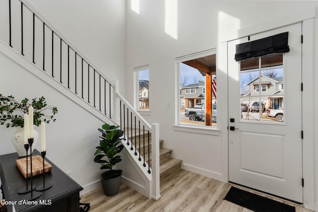 foyer entrance with a wealth of natural light, baseboards, and light wood finished floors