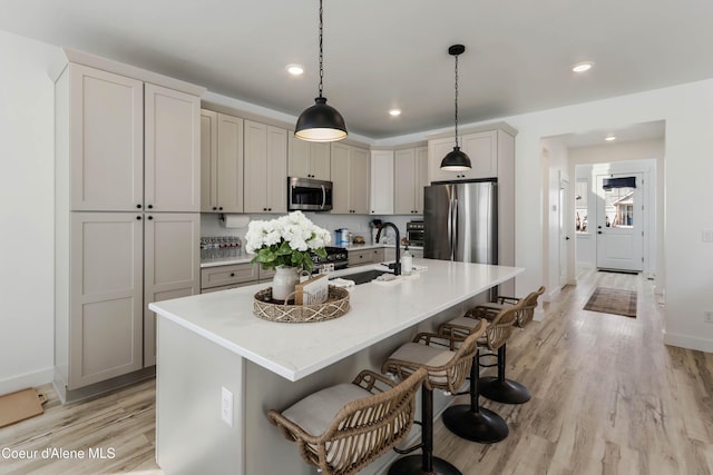 kitchen featuring a sink, stainless steel appliances, a kitchen bar, and light wood-type flooring