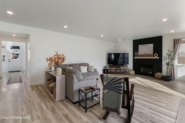 living area with recessed lighting, baseboards, a fireplace, and light wood finished floors