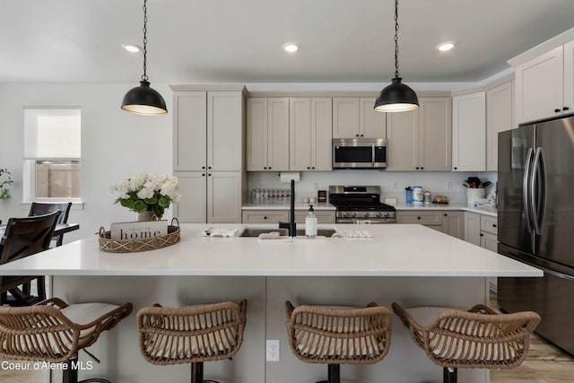 kitchen with a sink, appliances with stainless steel finishes, a breakfast bar, and light countertops