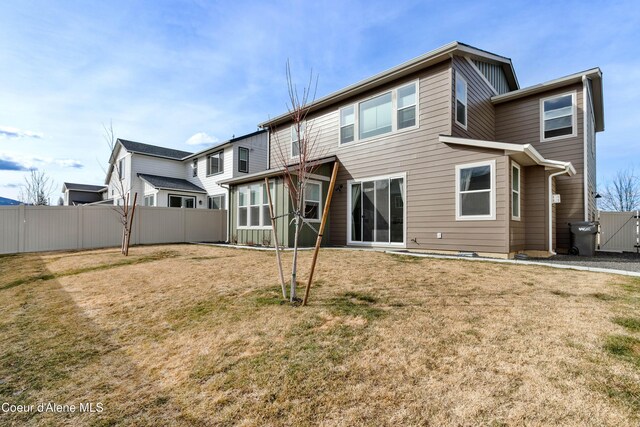 back of house featuring a lawn and fence