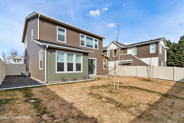 rear view of property with a yard, cooling unit, a fenced backyard, and board and batten siding