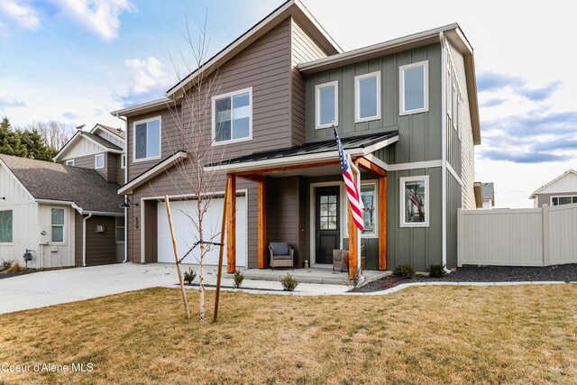 view of front of property with fence, a standing seam roof, an attached garage, a front lawn, and board and batten siding