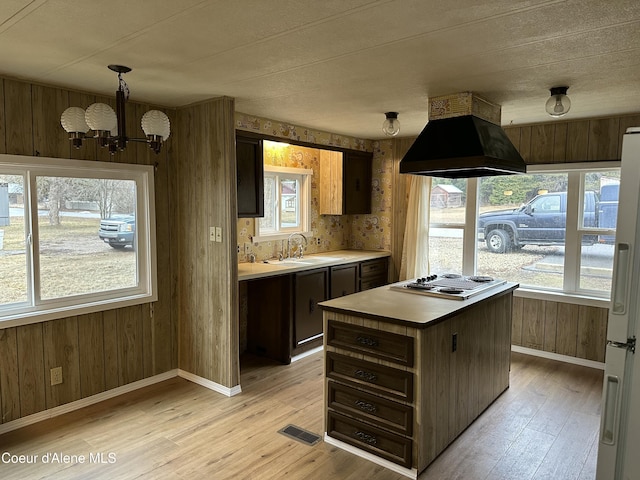 kitchen featuring visible vents, premium range hood, a sink, stainless steel electric stovetop, and light wood-type flooring