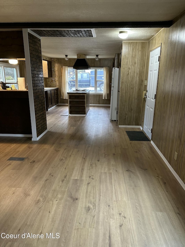 interior space with visible vents, wooden walls, baseboards, beam ceiling, and wood finished floors