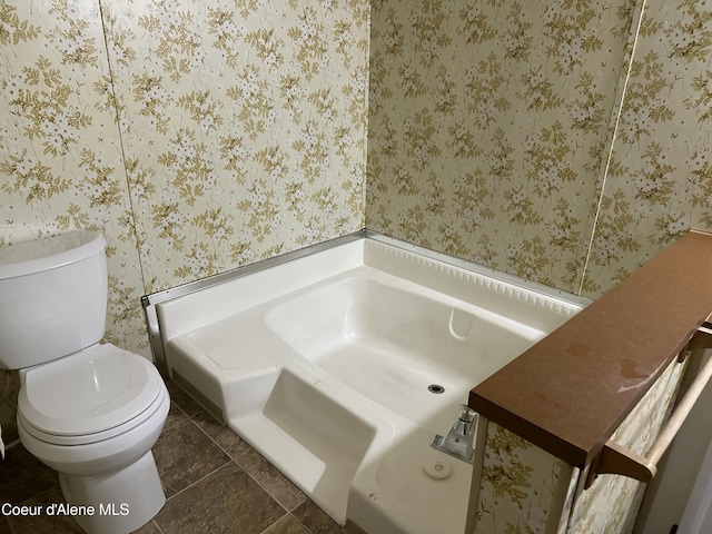 bathroom featuring wallpapered walls, a garden tub, and toilet