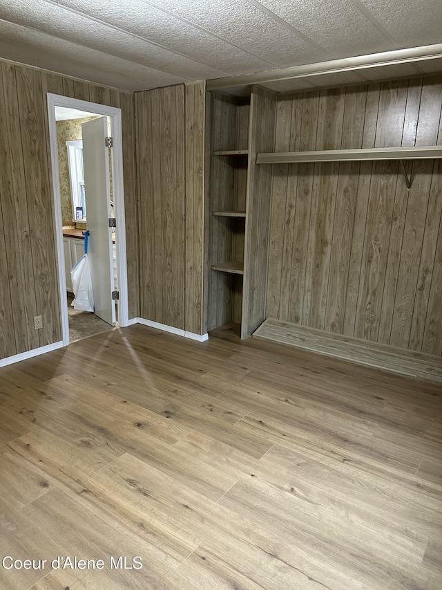 unfurnished bedroom featuring wood-type flooring and wood walls