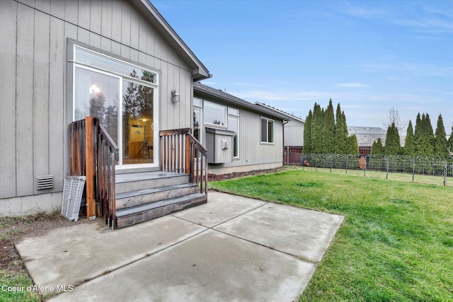 rear view of house featuring visible vents, board and batten siding, fence, a lawn, and a patio