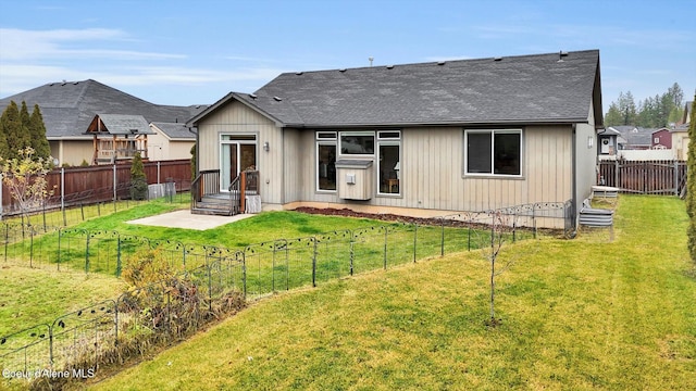 back of house with a lawn, a fenced backyard, entry steps, and a shingled roof