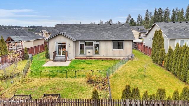 back of house featuring a lawn, roof with shingles, a fenced backyard, and a patio area