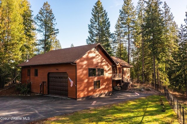 view of side of home featuring stairs, aphalt driveway, fence, and a garage