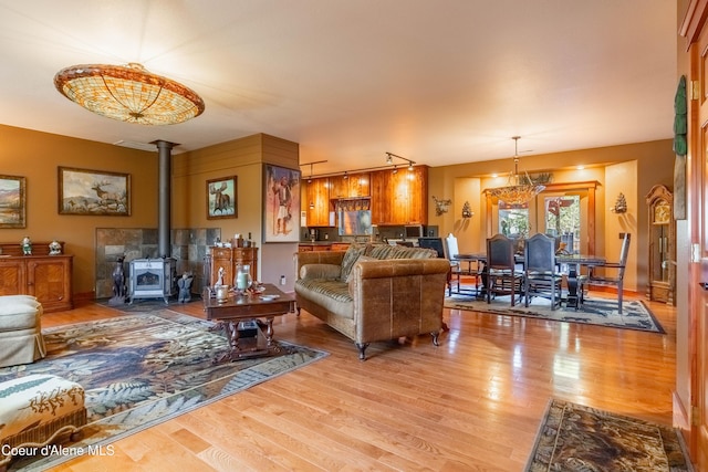 living room featuring track lighting, light wood-type flooring, and a wood stove