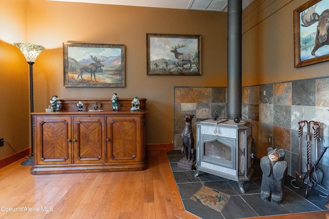 details with visible vents, a wood stove, baseboards, and wood finished floors