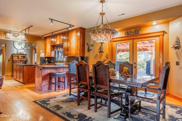 dining area with visible vents, light wood-style flooring, and french doors