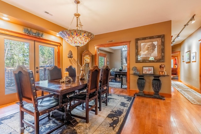 dining space featuring visible vents, light wood finished floors, baseboards, rail lighting, and french doors