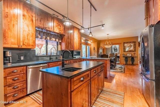 kitchen featuring dark countertops, an island with sink, appliances with stainless steel finishes, and a sink