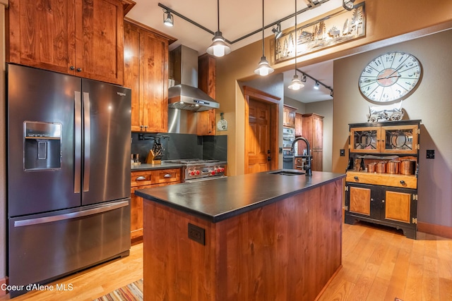 kitchen featuring dark countertops, appliances with stainless steel finishes, wall chimney exhaust hood, and a sink