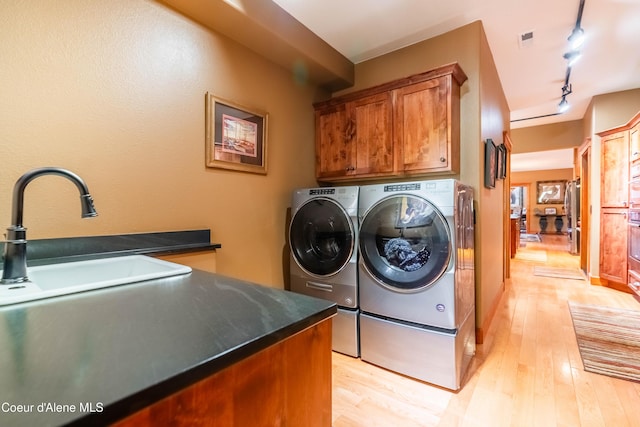 clothes washing area with visible vents, cabinet space, light wood-style flooring, and separate washer and dryer